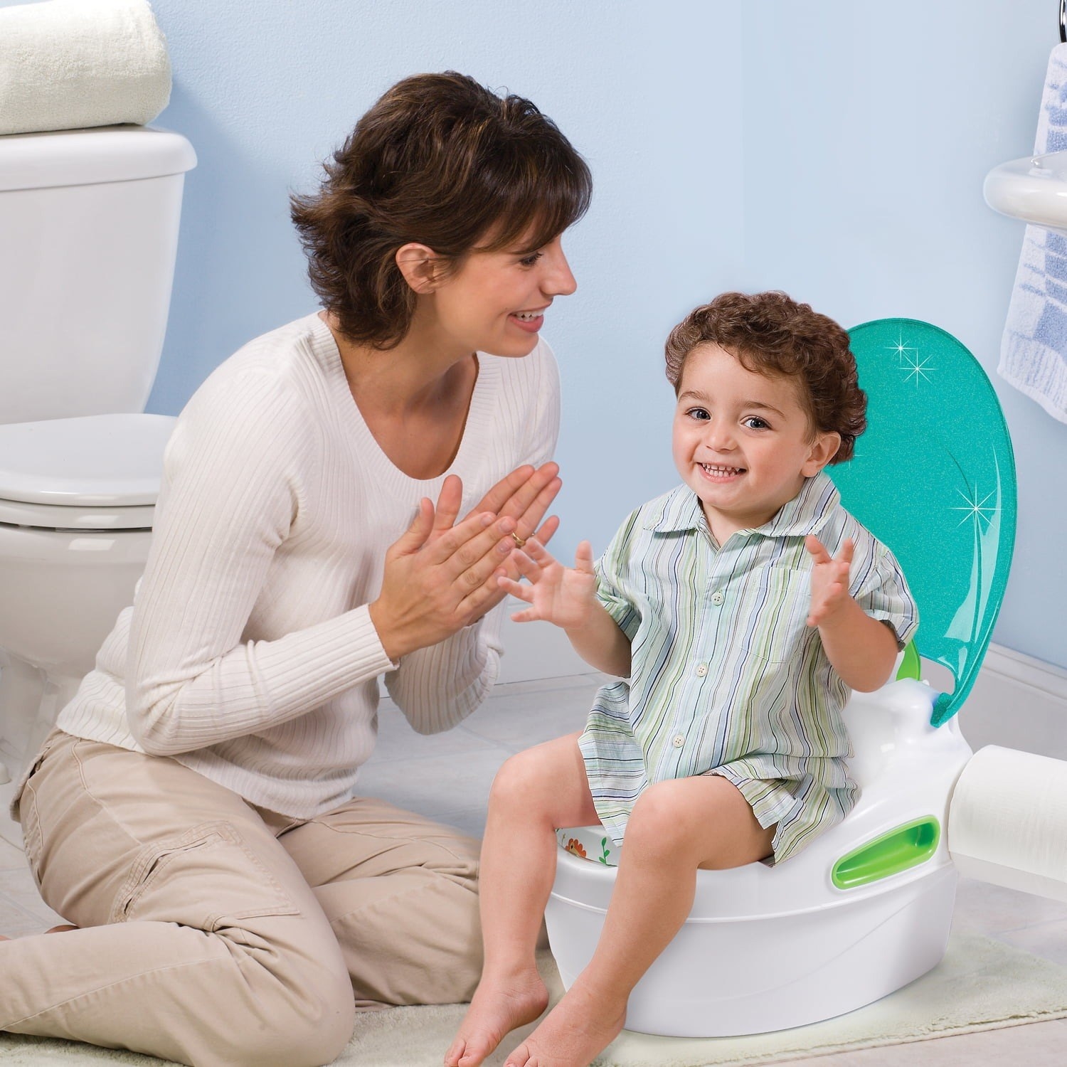 A parent clapping as her child sits on the training potty.