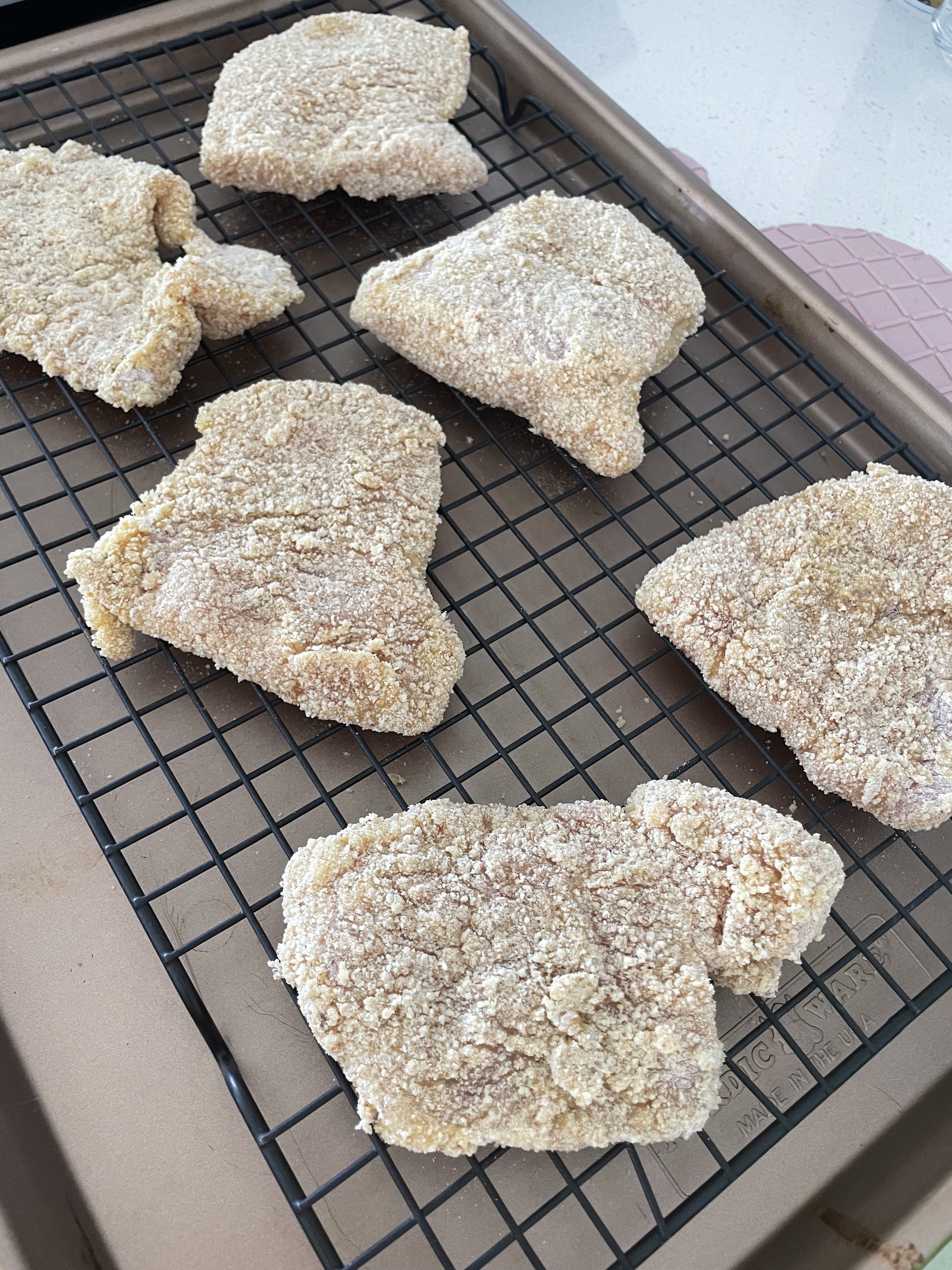Breaded chicken on a sheet pan and baking rack