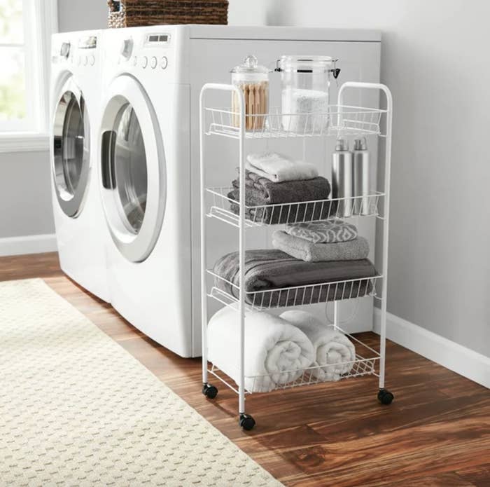 a rolling wire cart in a laundry room with folded towels and detergents on it