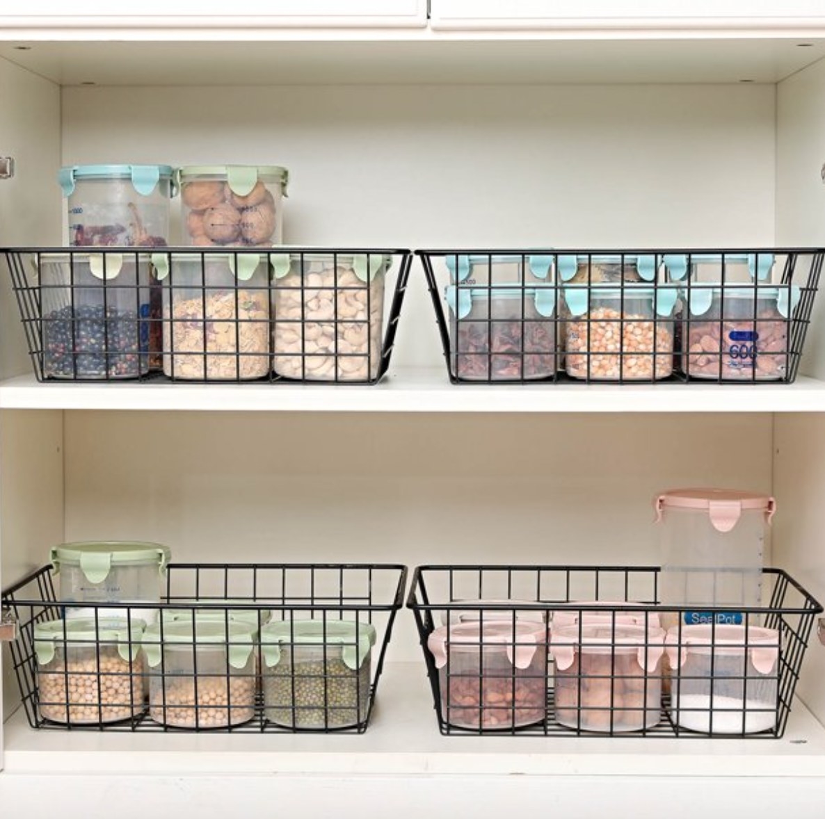 four wire baskets with groceries organized in them inside of a pantry