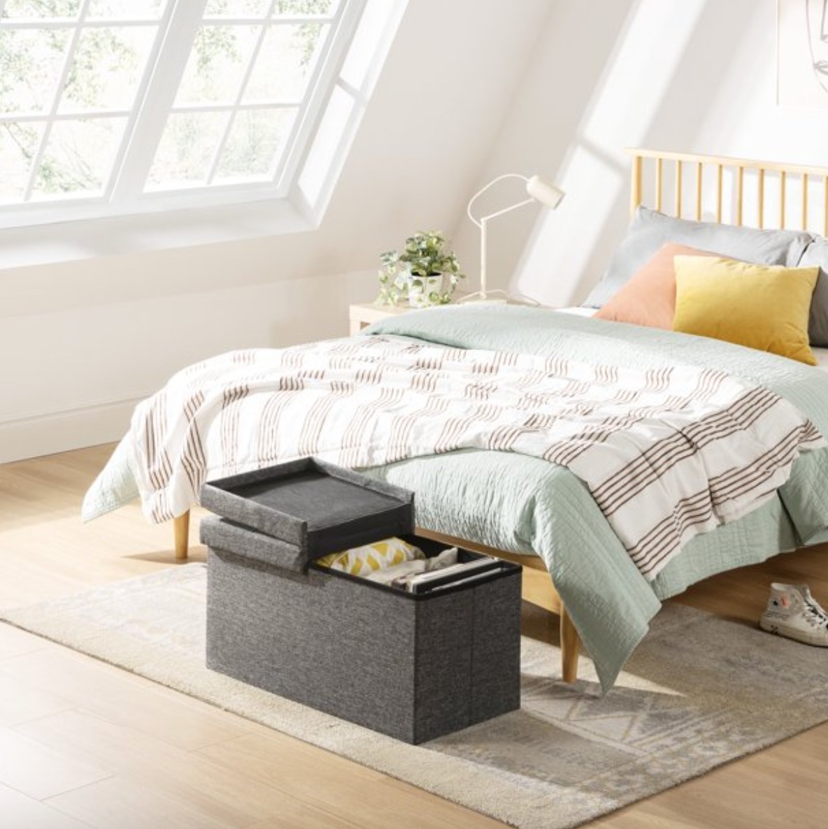 a bedroom with a made bed and a ottoman with a removable top for storage