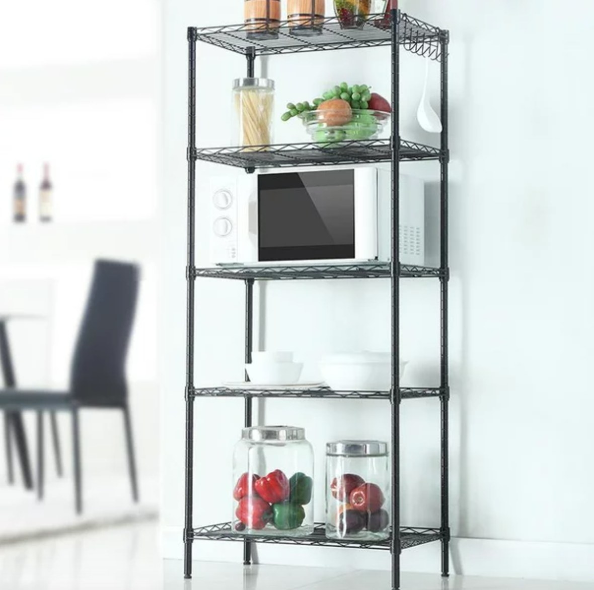 a wire rack with a microwave and kitchen supplies on it