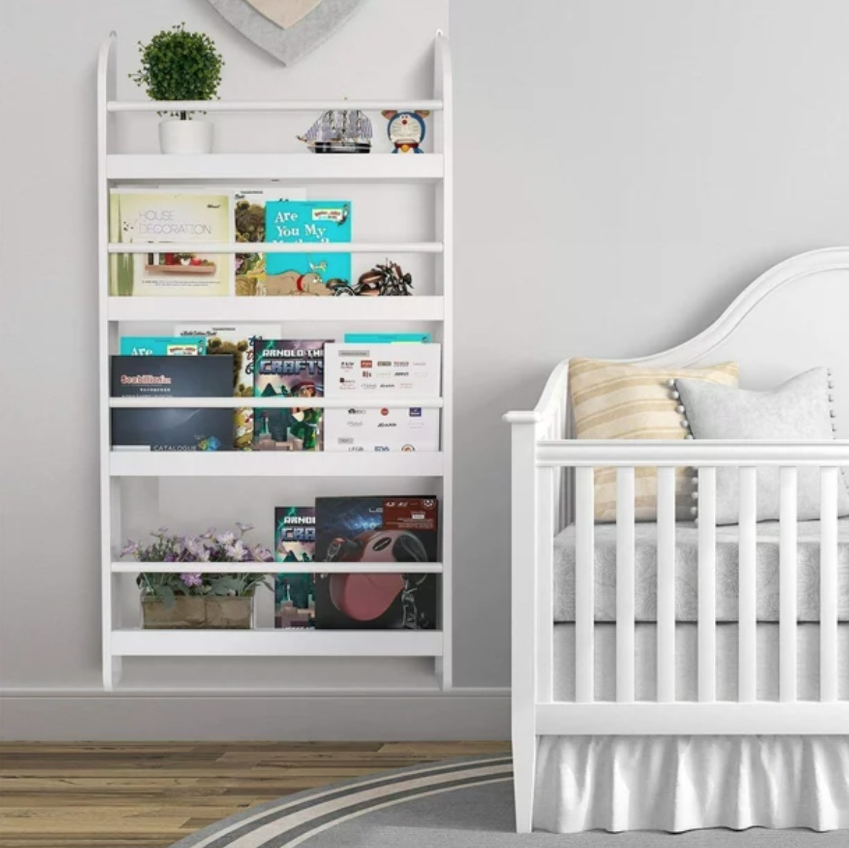 a mounted bookshelf filled with books and decor next to a crib