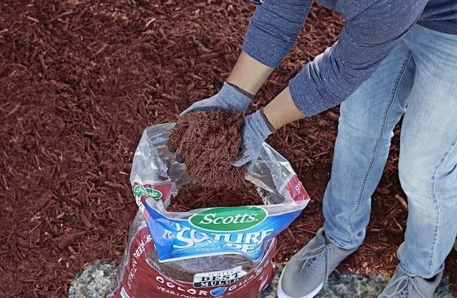 A person spreading the mulch in a yard