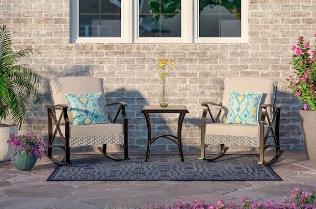 The patio set with two rockers with cushions and a matching table on a patio