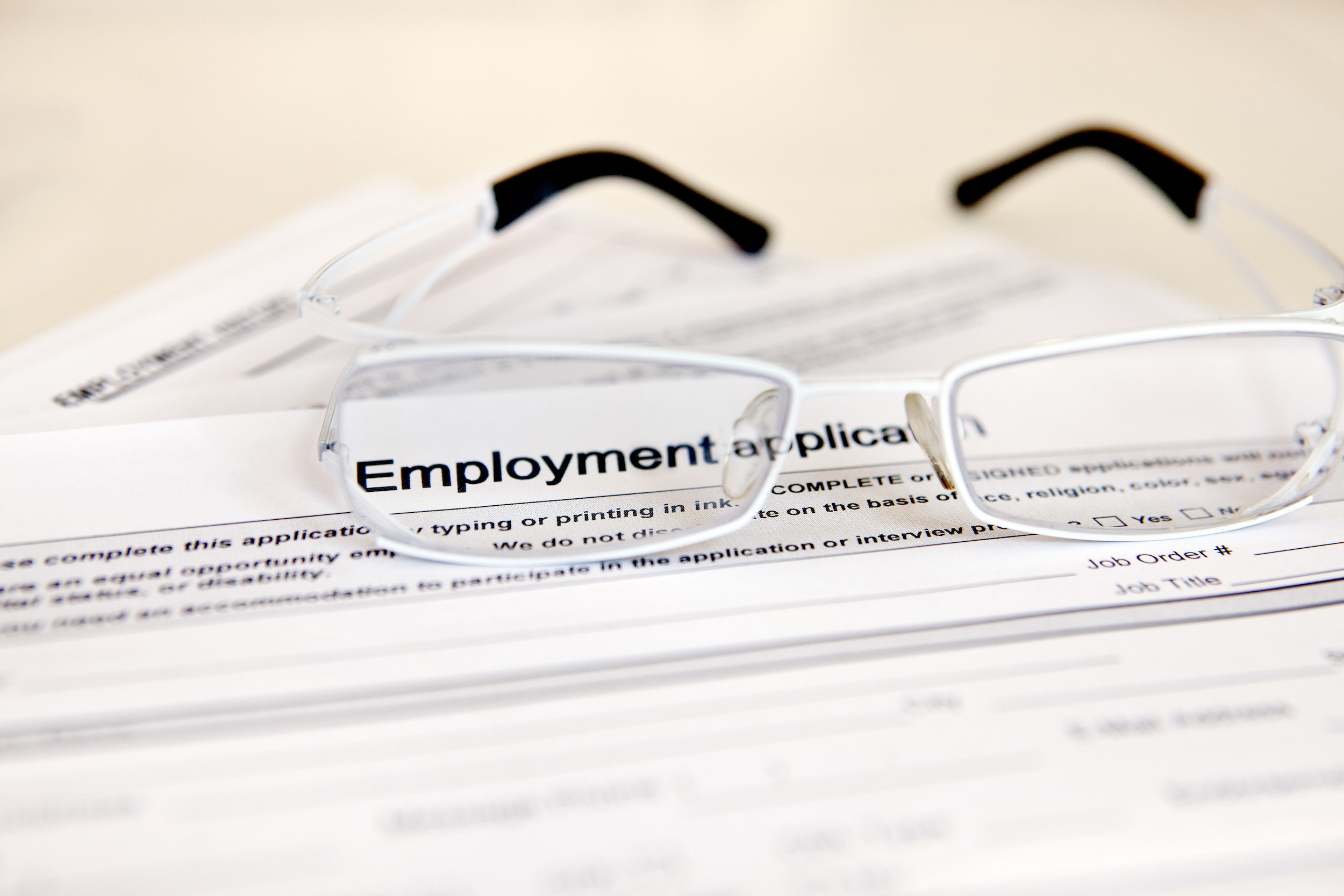 An employment application with a pair of eyeglasses on top of it