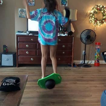 Reviewer's photo of child using green and black pogo ball indoors for scale