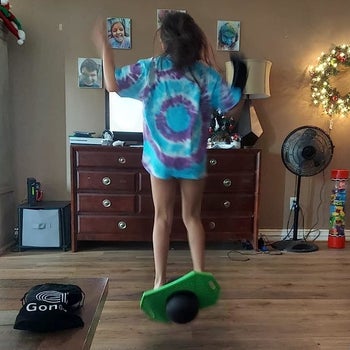 Reviewer's photo of child using green and black pogo ball indoors for scale