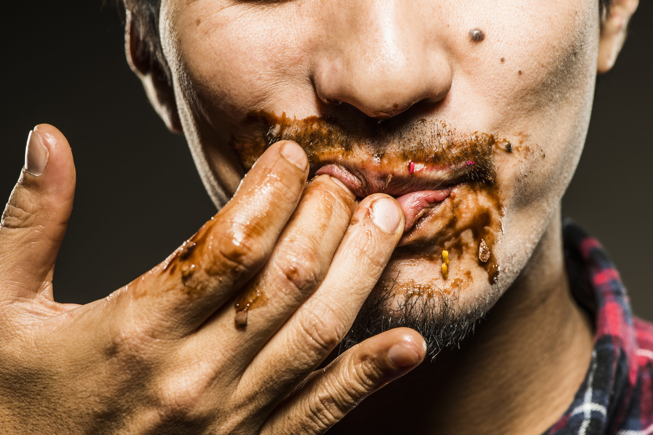 Man licking dirty fingers after eating a meal