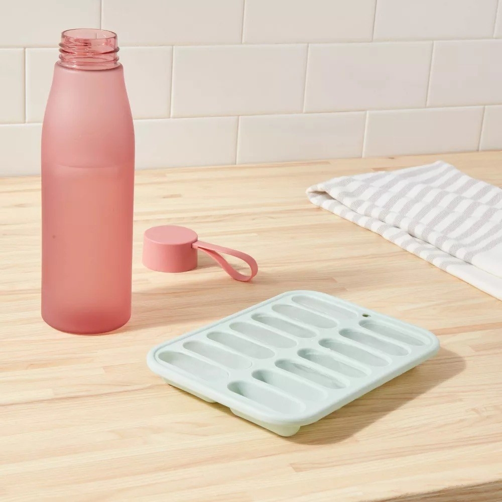 Green ice cube tray next to pink water bottle