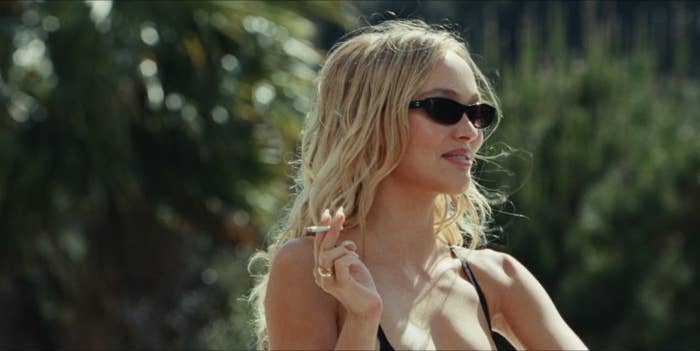 Lily-Rose Depp holding a cigarette and wearing sunglasses in a scene from The Idol