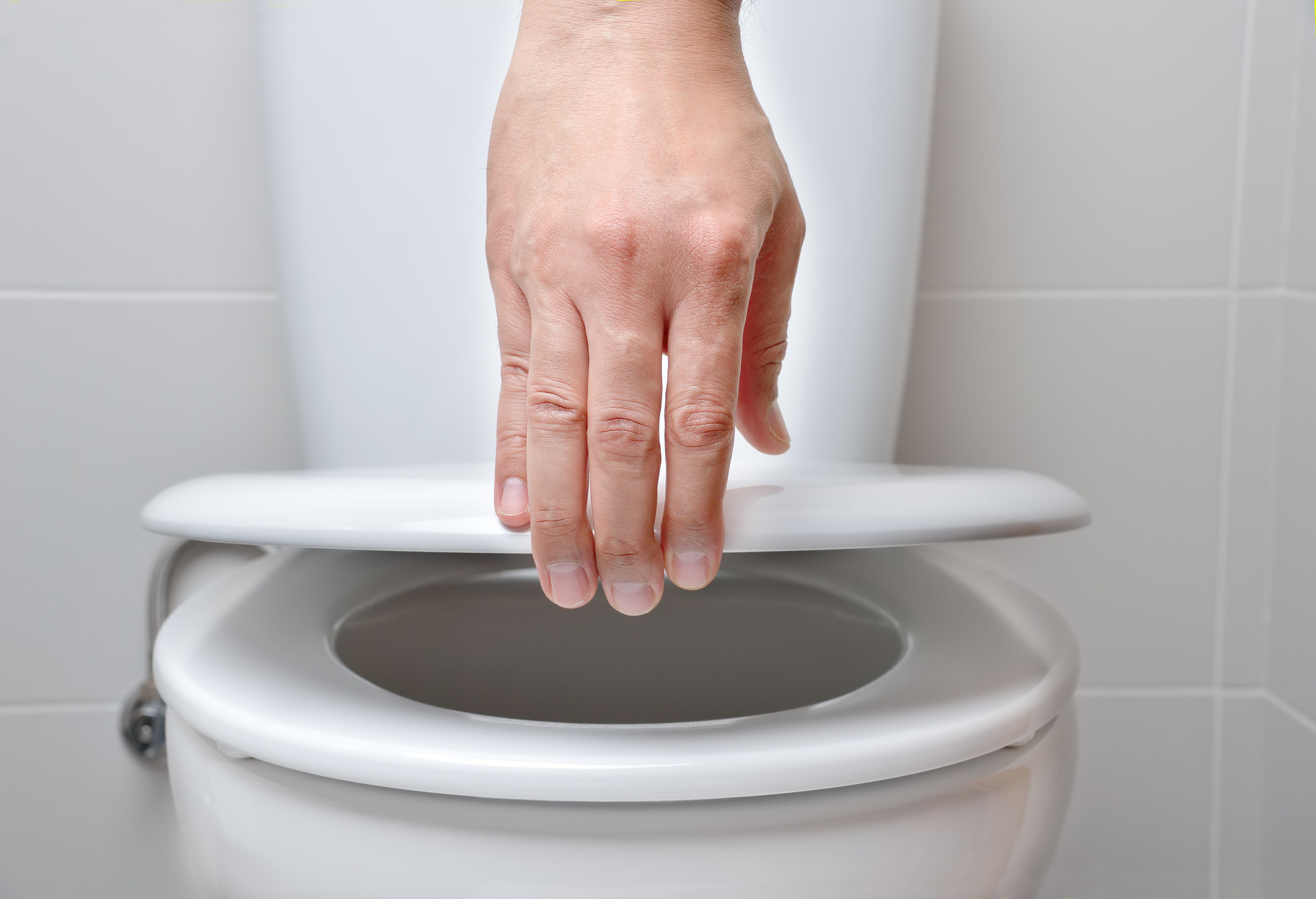 Hand of man closing toilet seat