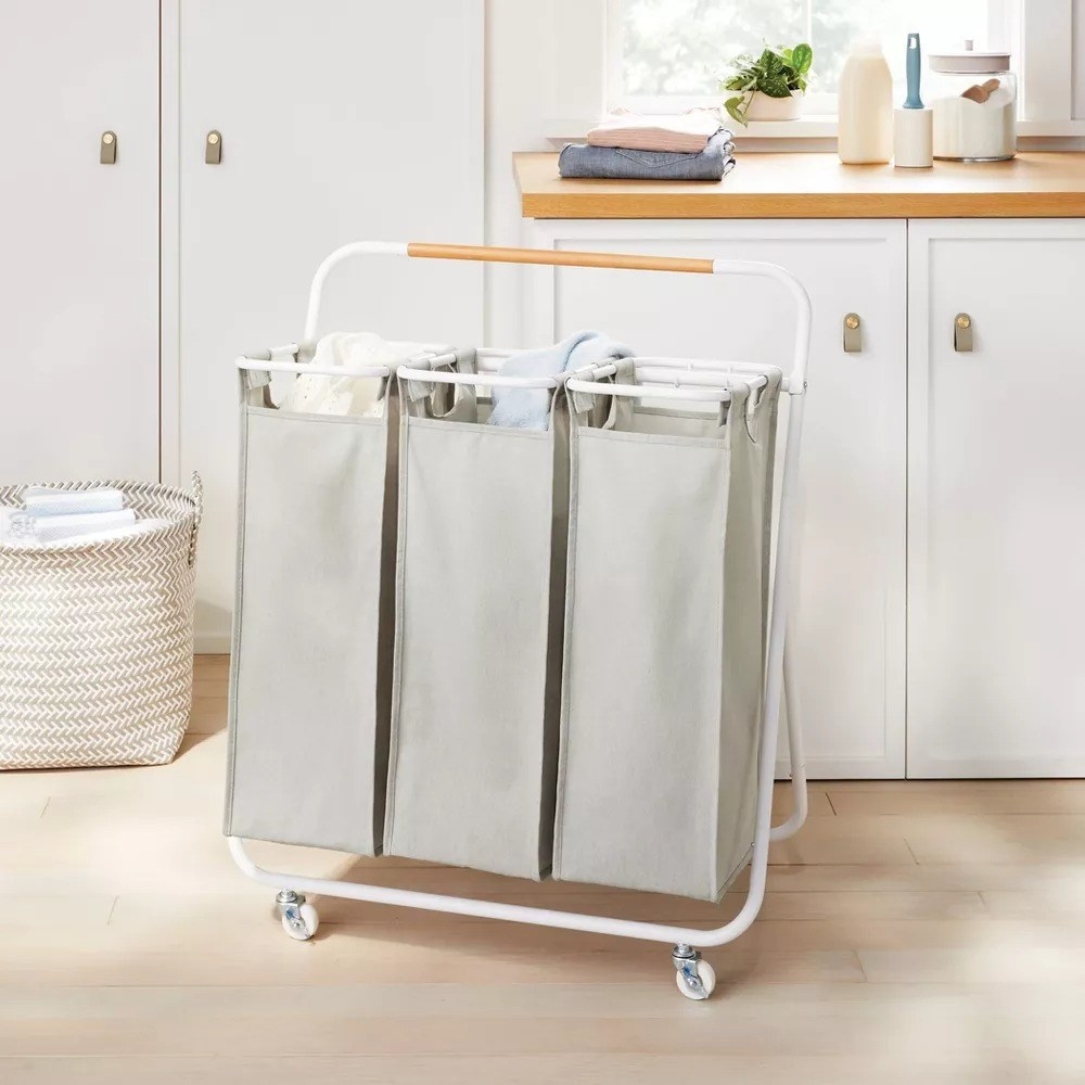 Three compartment gray rolling laundry sorter in laundry room