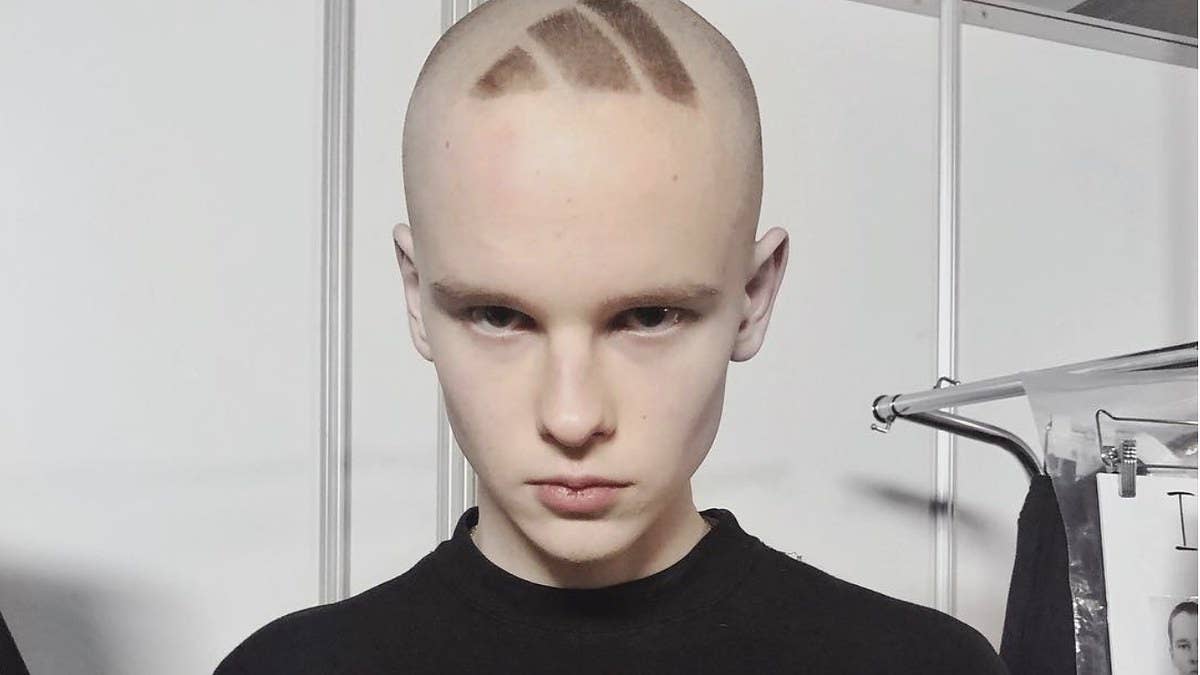 A model walking in Gosha Rubchinskiy's Fall/Winter 2018 runway show had an Adidas logo shaved into his head. 