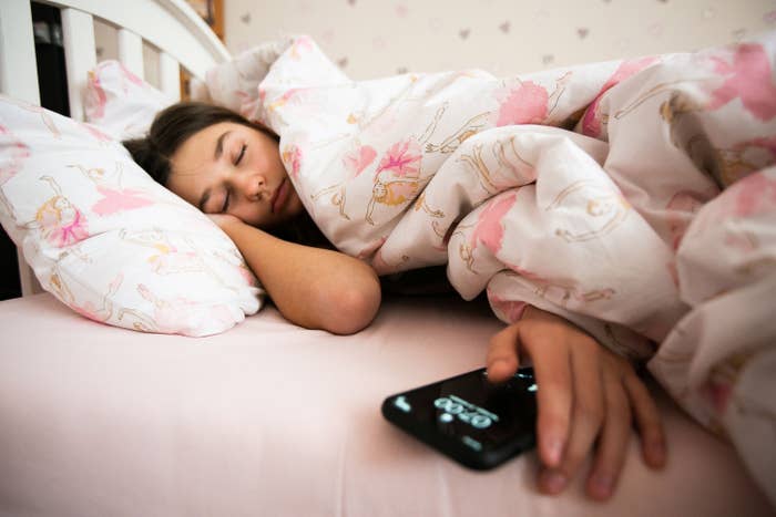 a girl in bed touching her phone
