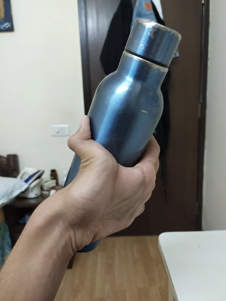 a person gripping a metal water bottle with the back of their hand