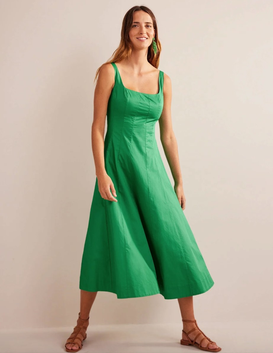 a model in a green square neck a-line midi dress and gladiator sandals