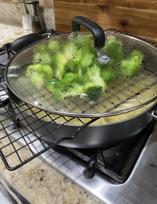 Broccoli steaming over cooking noodles