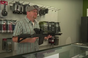 gun store owner holding weapon