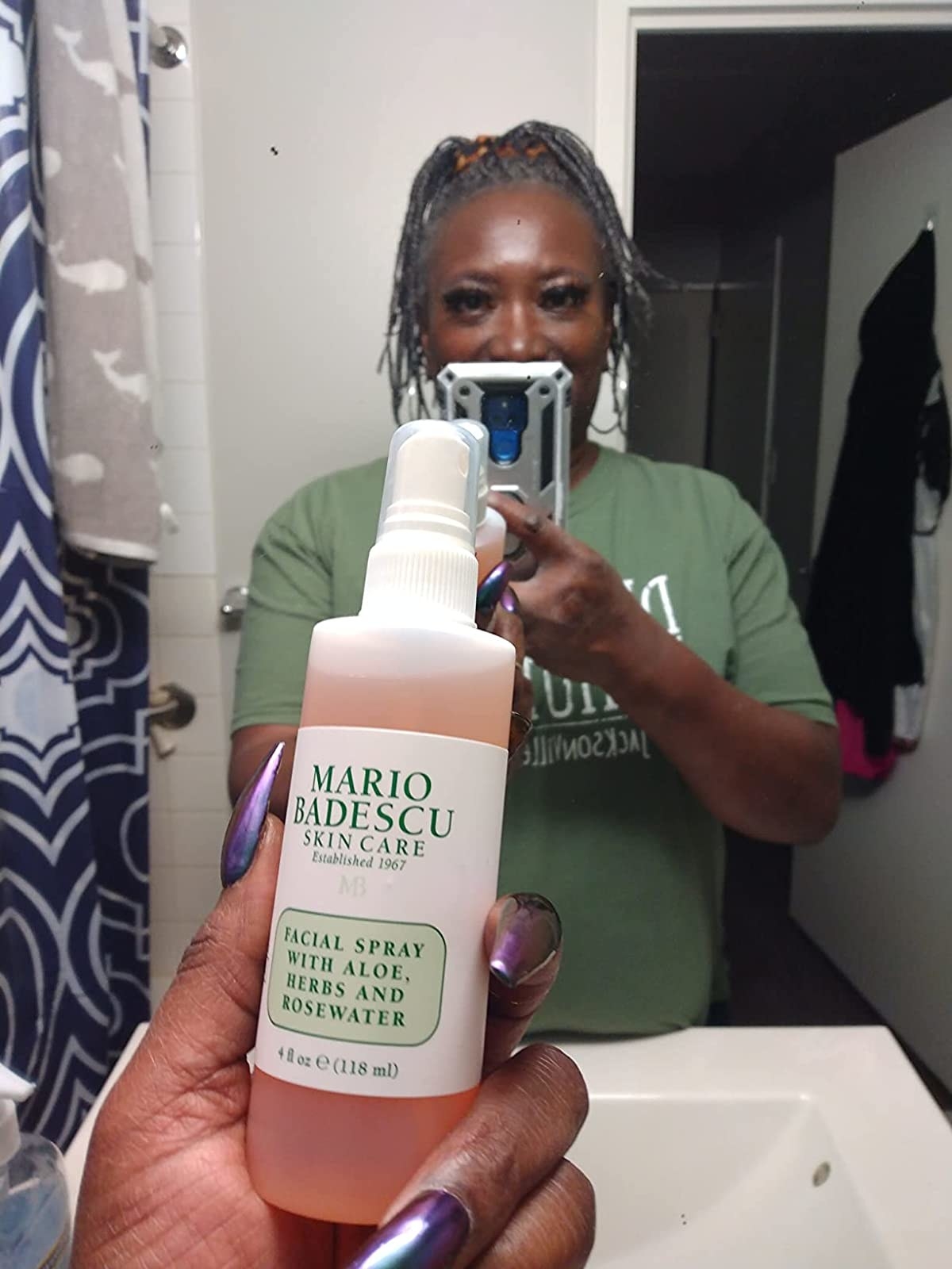 A reviewer holding the pink, white and green spray