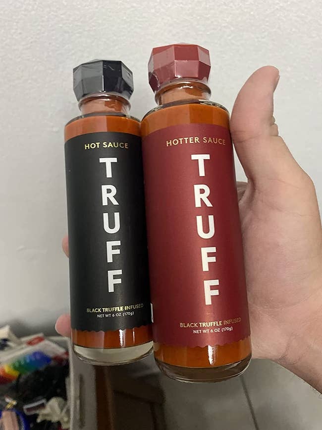 image of reviewer holding up a bottle of the hot and hotter sauces