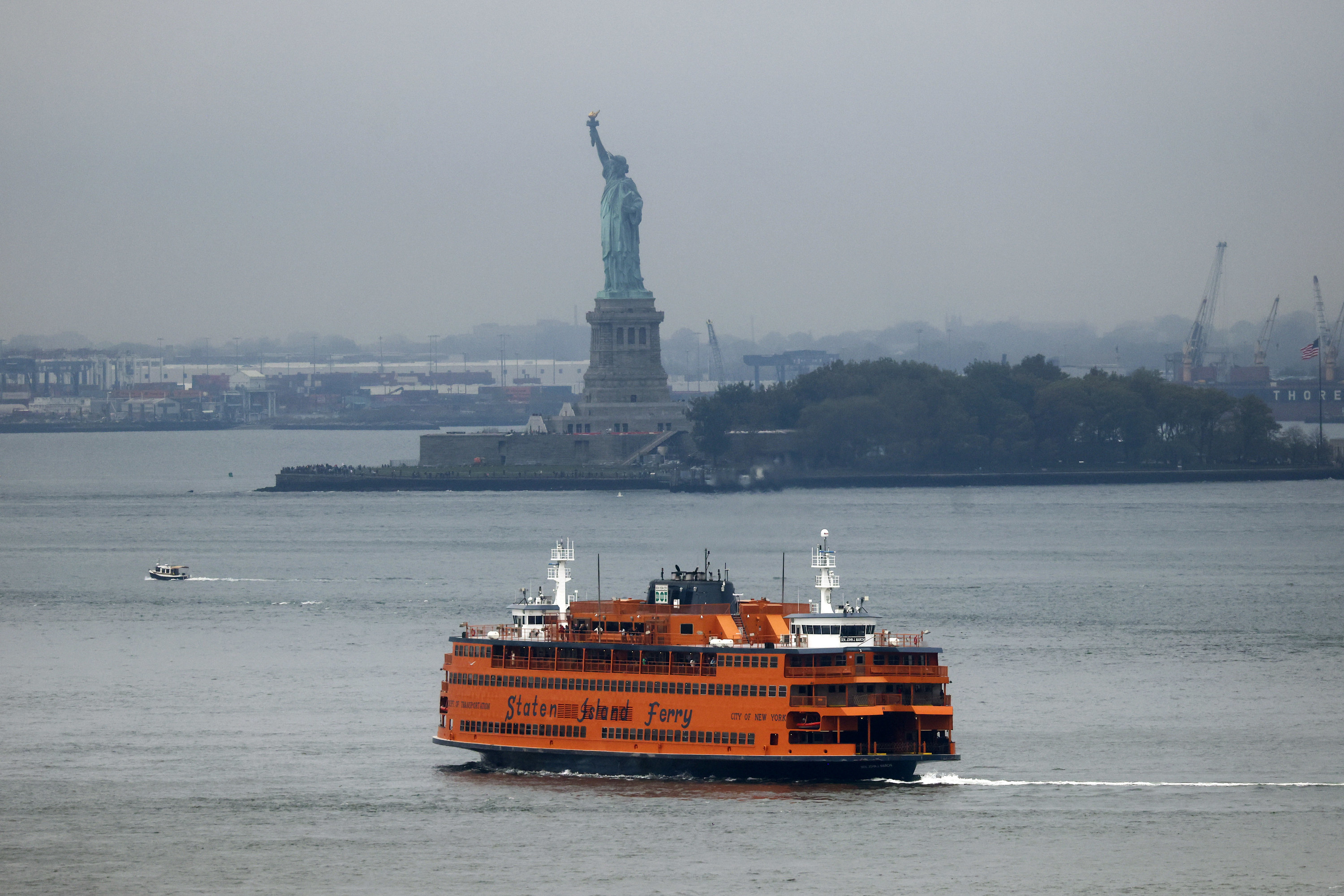 A Staten Island Ferry on the water with the Statue of Liberty in the background