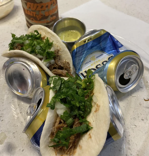 Someone using empty beer cans to hold their tacos