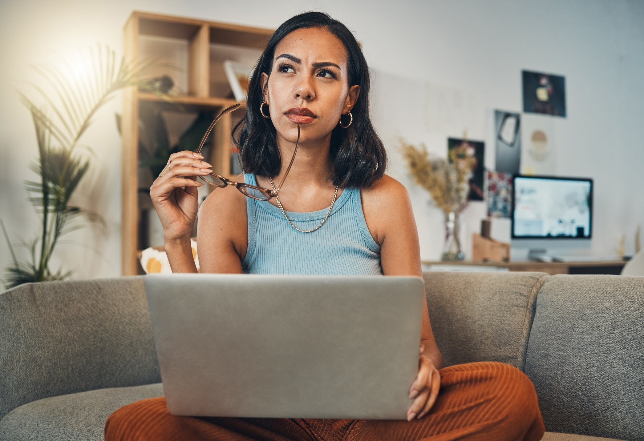 A woman thinking while using laptop at home