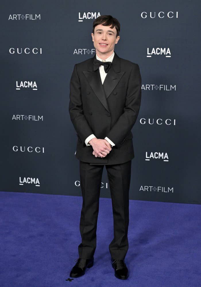 Elliot Page smiles on the red carpet of a formal event wearing a tux