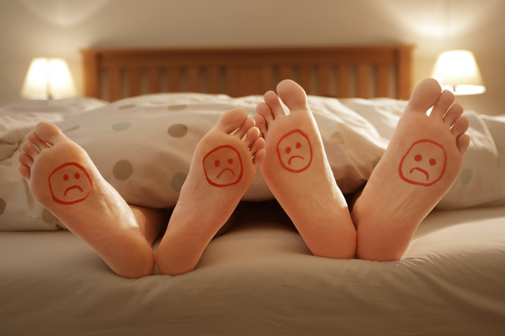 Two pairs of feet with sad faces drawn on them