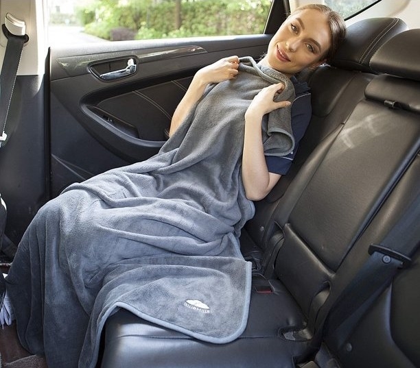 Model sitting in car with grey blanket draped over them