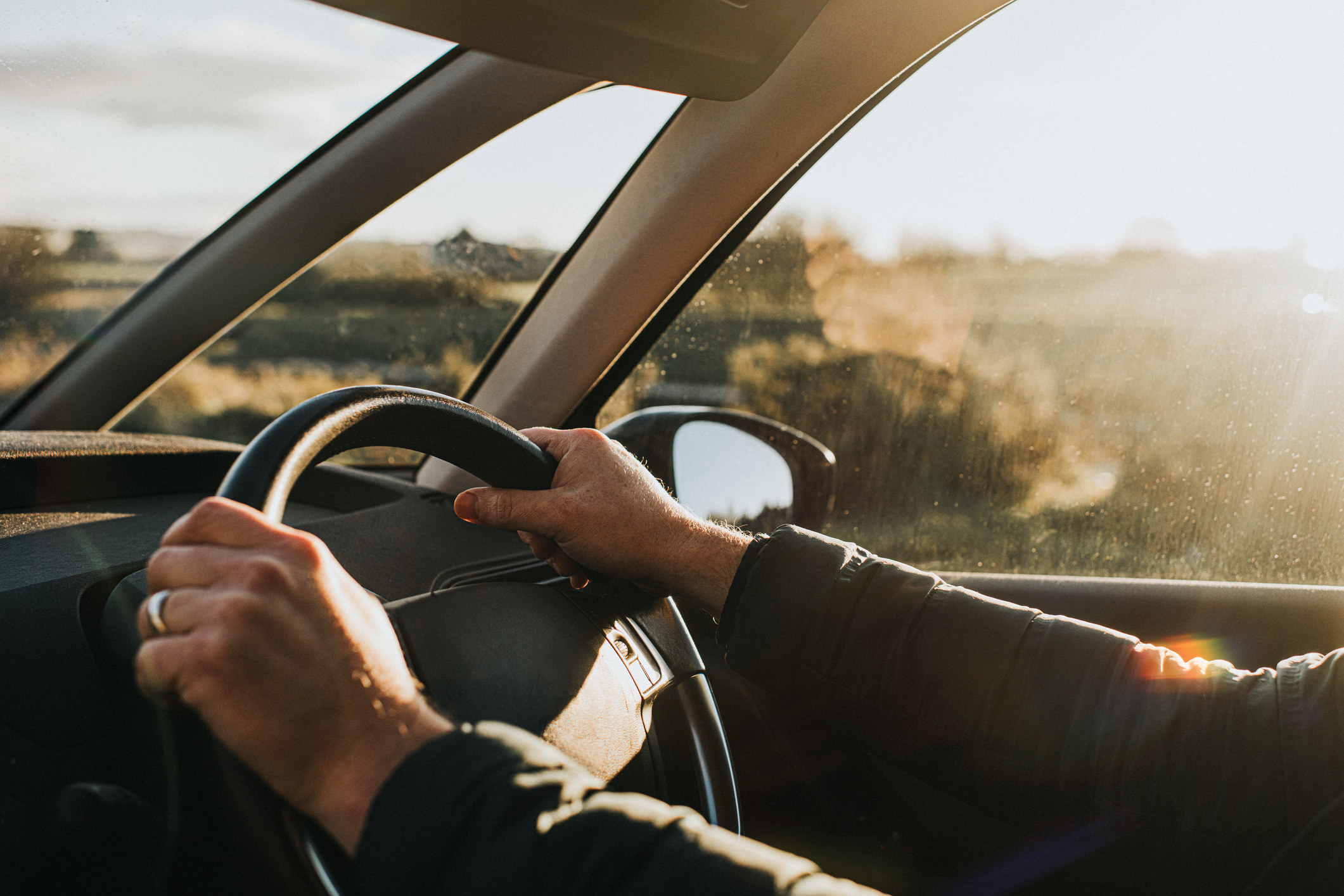 Two hands on a steering wheel in a car