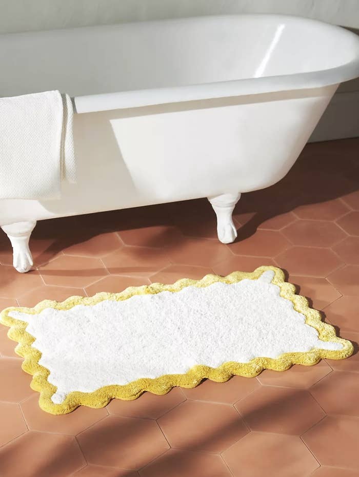 the yellow trimmed bath mat outside of tub