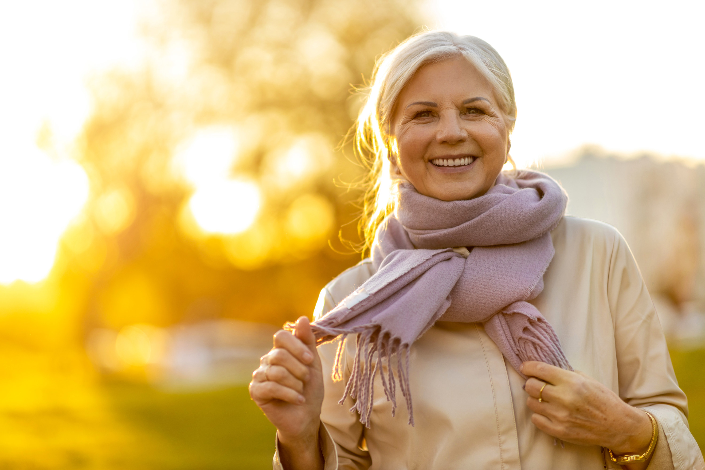 A woman smiles as the sun sets behind her
