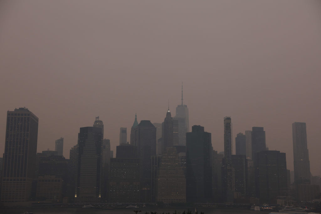 The Manhattan skyline stands shrouded in a reddish haze