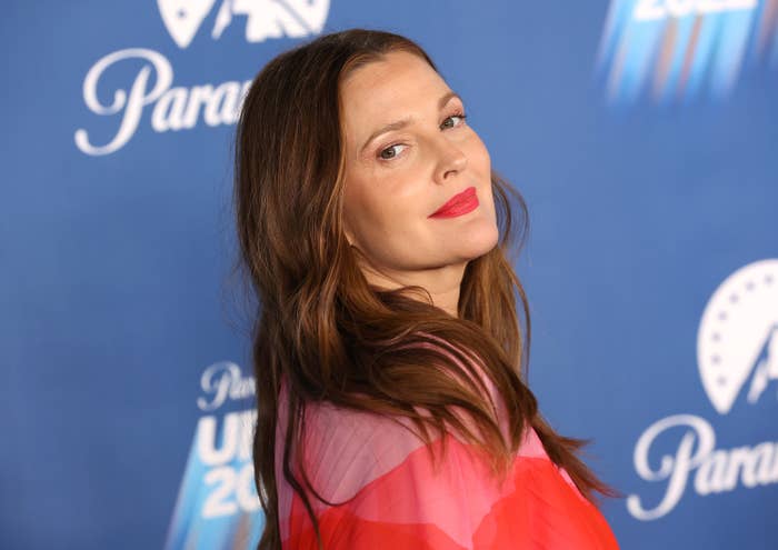 Drew looks over her shoulder as she smiles at a red carpet event