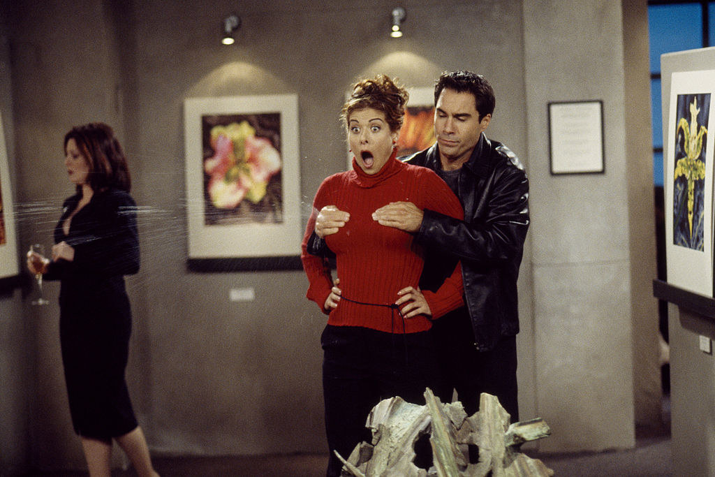 Will Truman, played by Eric McCormack, holding onto Grace&#x27;s breasts from behind as liquid squirts out while they stand inside an art gallery