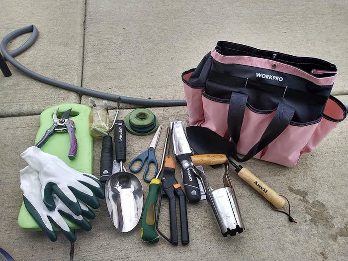 Reviewer&#x27;s photo of the garden tote in the color Pink, plus a whole bunch of tools that fit inside it to demonstrate how roomy it is