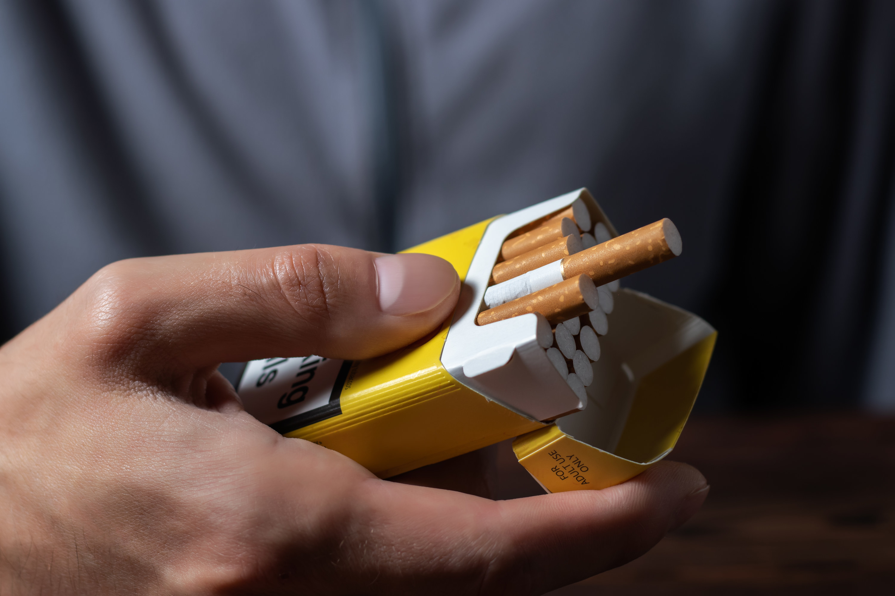 A hand holding a pack of cigarettes