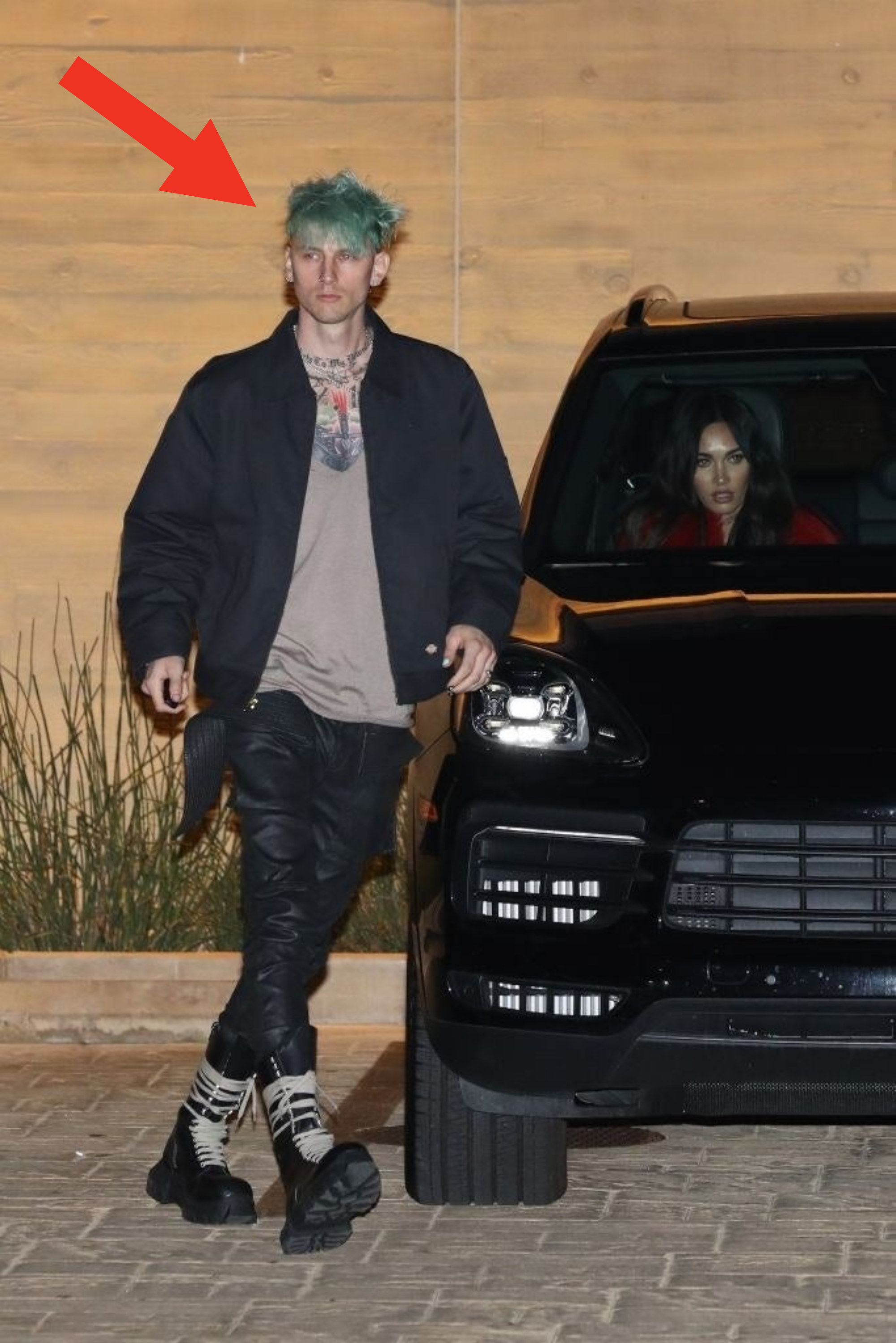 MGK has blue-ish hair as he walks around a car that Megan is sitting in