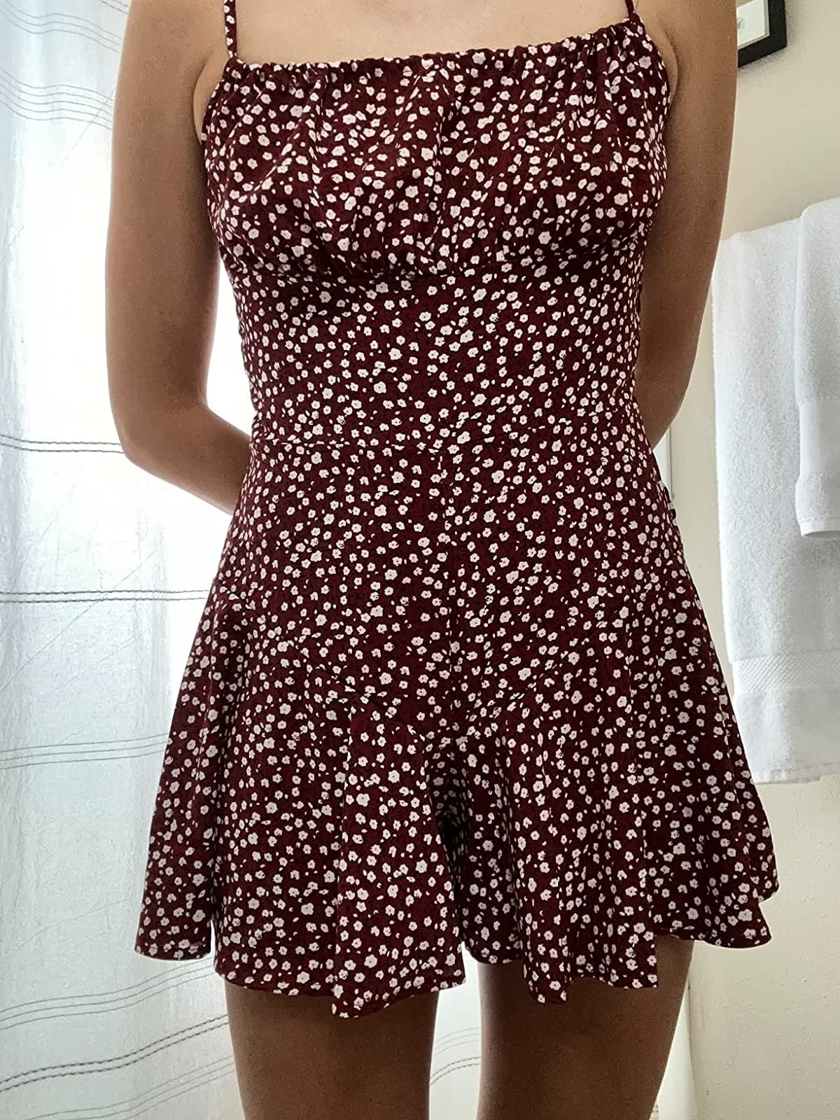 Reviewer wearing red and white floral spaghetti strap romper