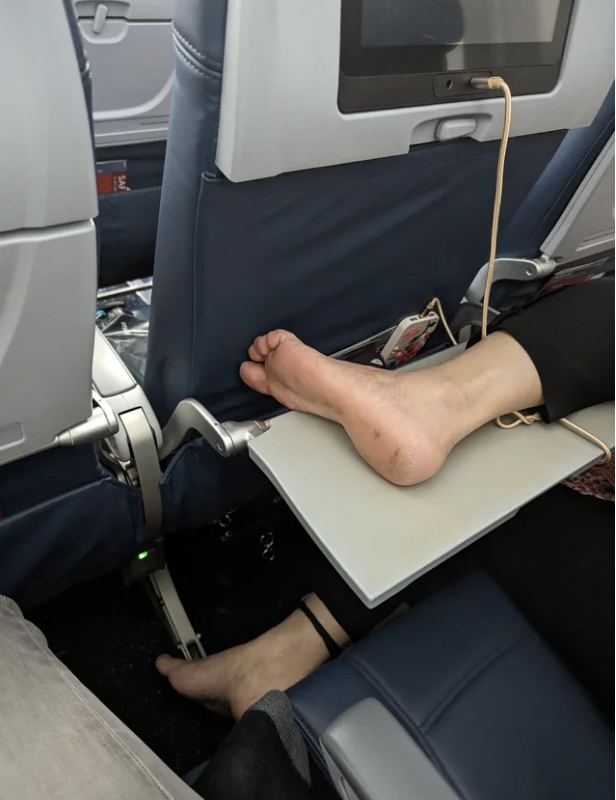person&#x27;s bare feet on the plane tray