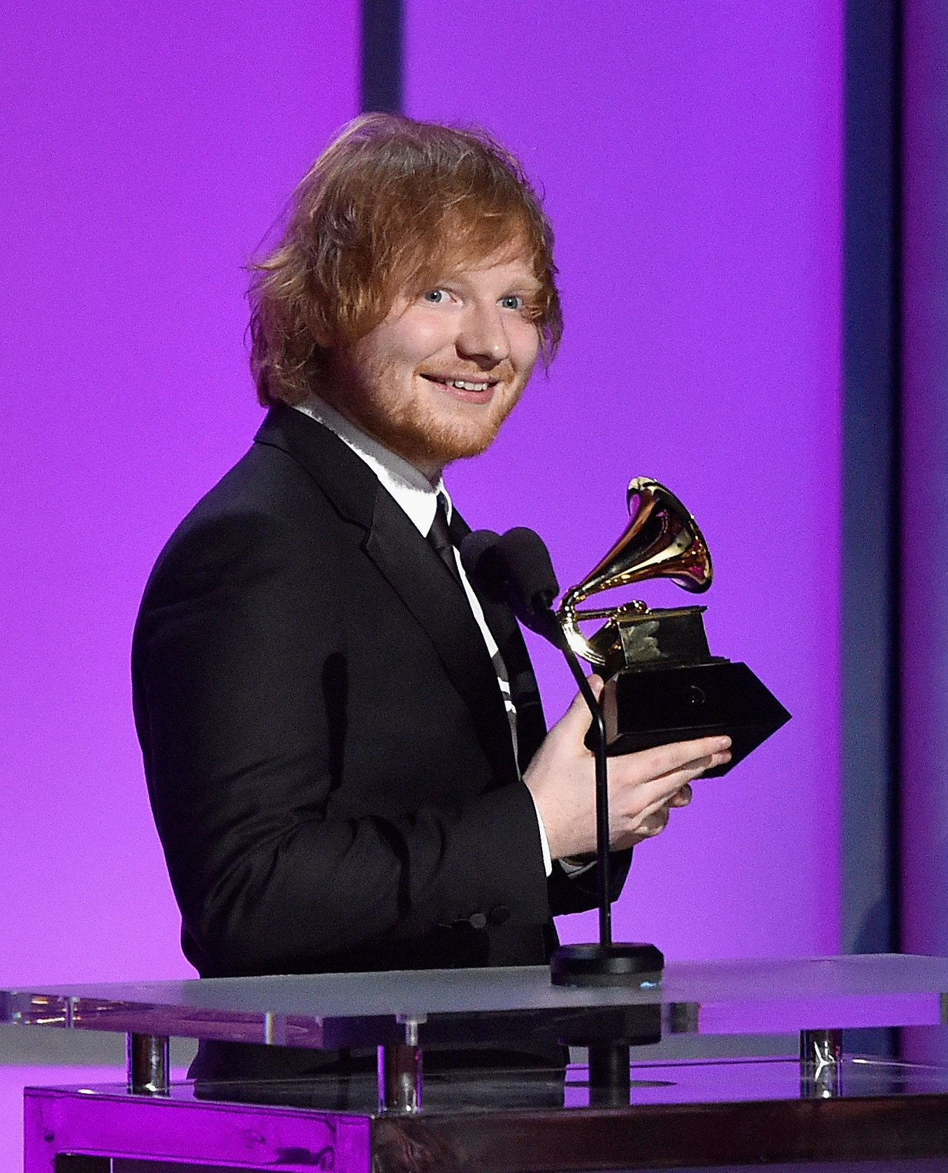 Ed onstage, smiling, and holding an award