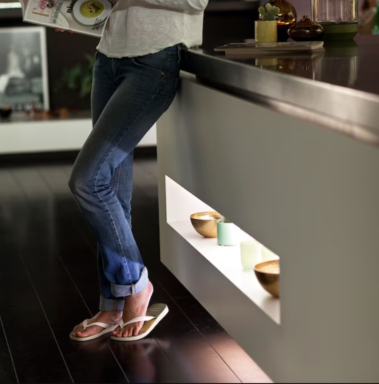 a model standing next to kitchen cabinets with the lights installed over decorative pottery