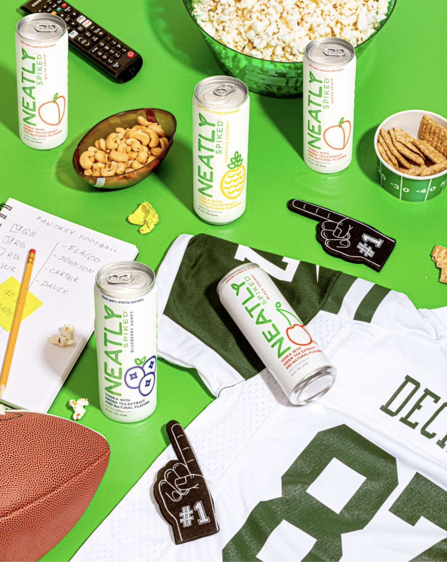 Cans of Neatly Spiked hard seltzers surrounded by football gear.