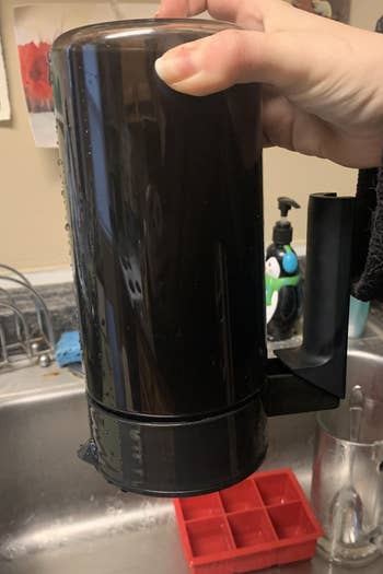 Reviewer holding coffee maker full of cold brew upside down to show how airtight it is