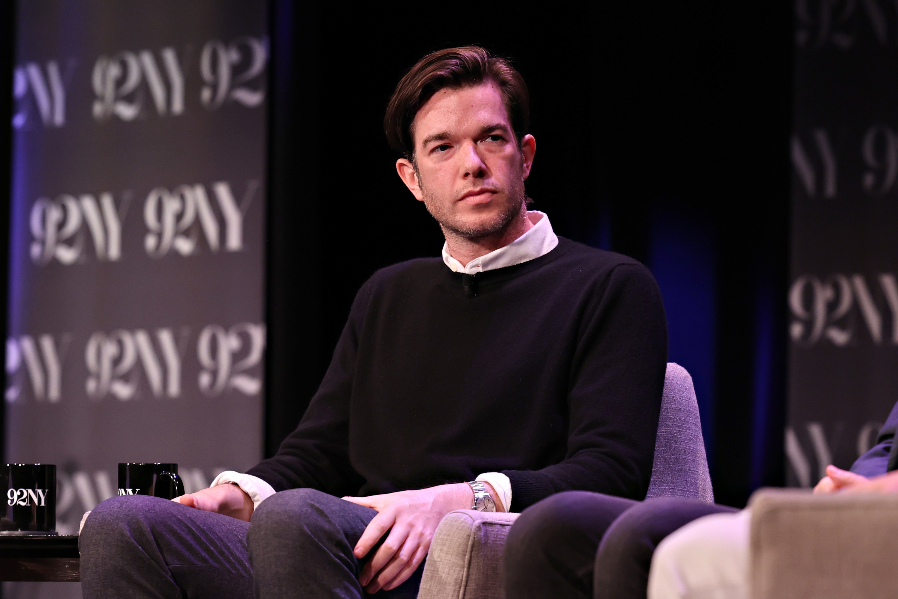 Close-up of John sitting onstage