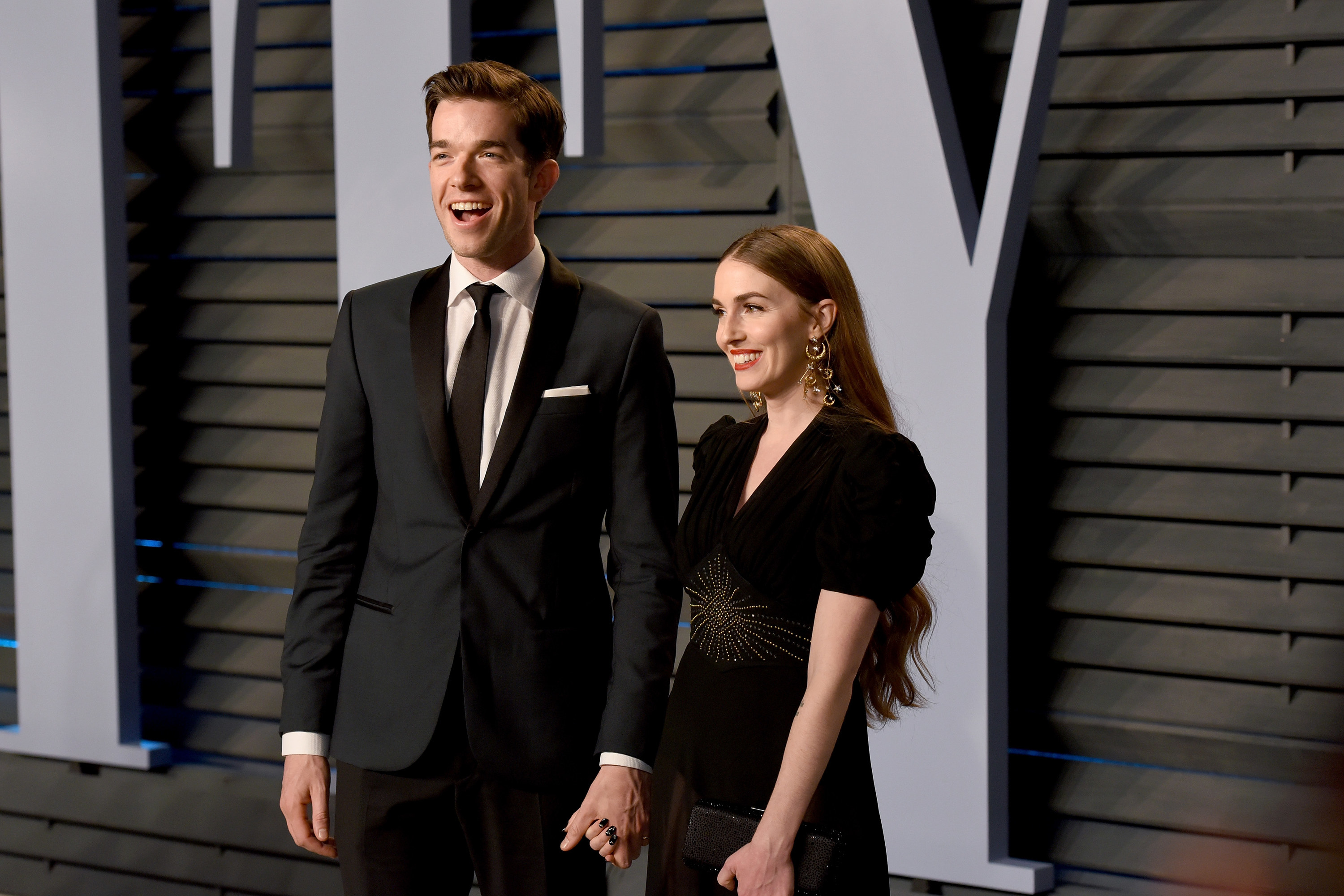 Close-up of John and Anna holding hands and smiling at a media event