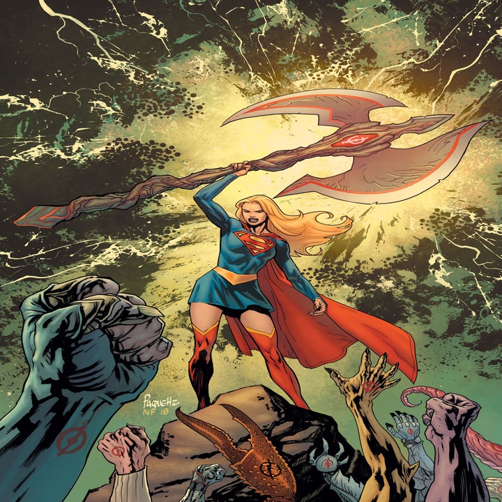 Kara Zor-El with blonde hair in the comics. She's holding up a large battle ax as she address a crowd