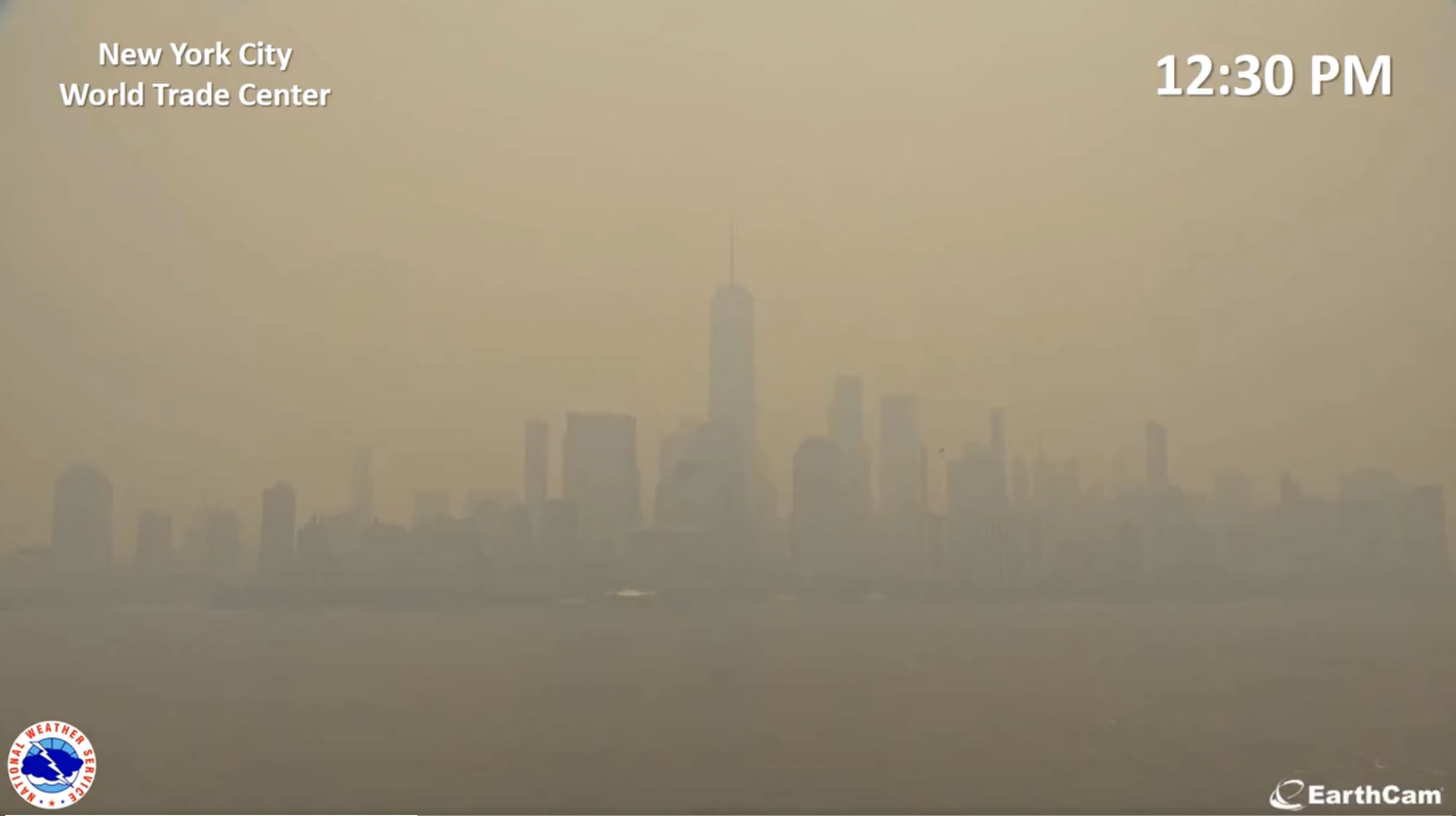 View of the downtown Manhattan skyline at 12:30 pm, with the sky a light orange